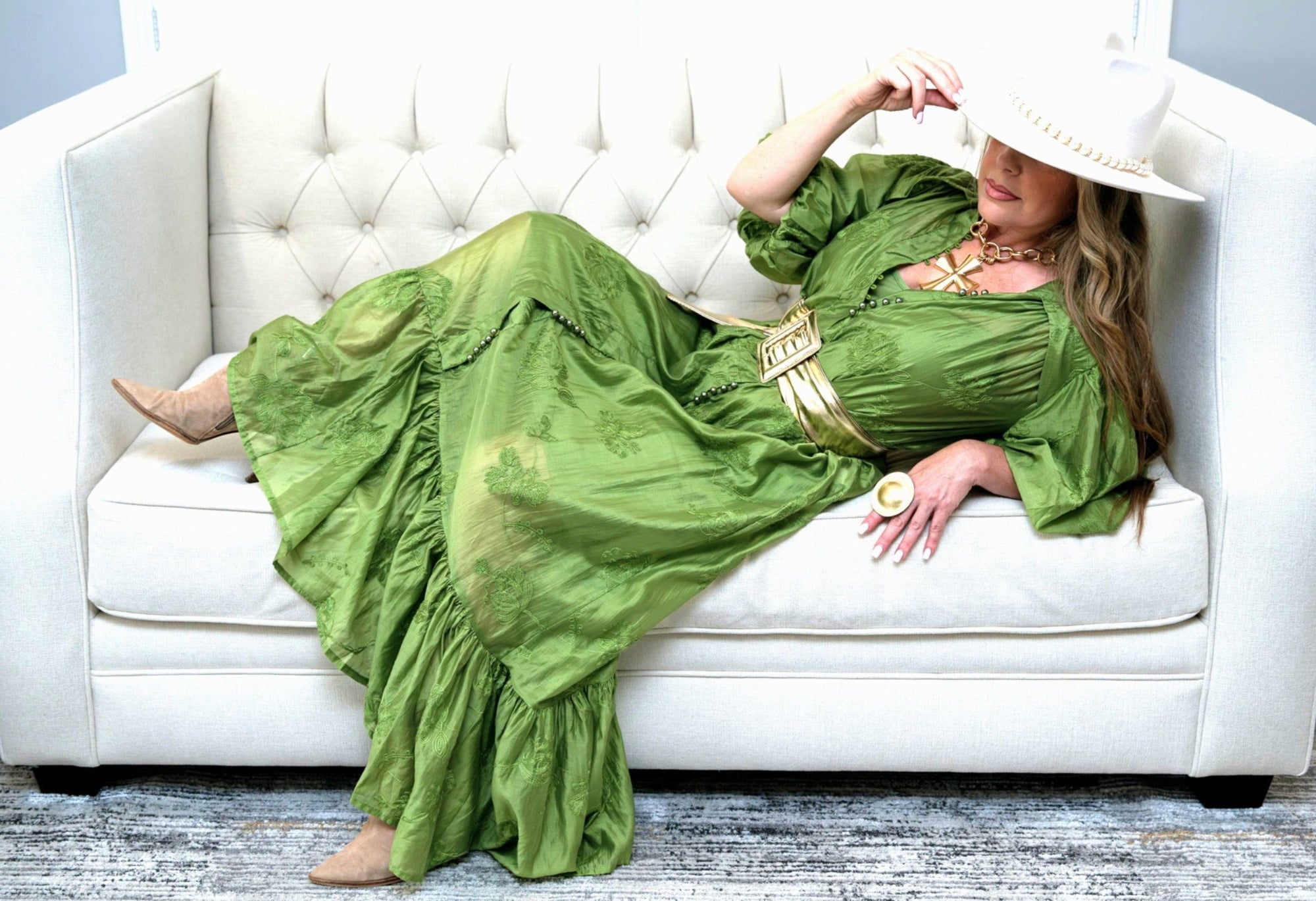 Woman in a green dress sitting on a white couch